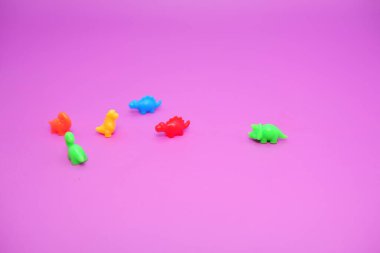 Pembe Arkaplanda Çeşitli Renklerde Plastik Oyuncak Dinozorları