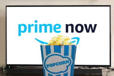 Amazon Prime Video logosu televizyonda ve önünde patlamış mısırla sergileniyor. TV konsepti üzerine filmler ve diziler izlemek. Resimli başyazı.