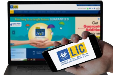  Mobil ekranda LIC Bank logosu ve bulanık web siteleri laptop ekranında görüntülendi. editoryal resim.
