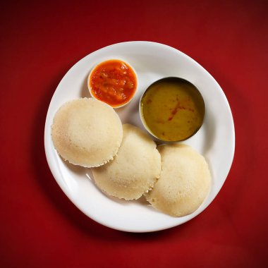 Idli, sambar ve turşulu. Güney Hindistan 'da kahvaltı sofrasında. Koyu kırmızı arka planda izole edilmiş. Yukarıdan görüntüle.