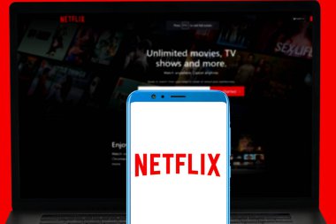 Mobil ekranda Netflix logosu ve onların bulanık web sitesi bilgisayar ekranında görüntülendi