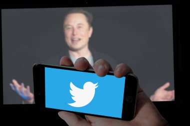 CHENNAI, INDIA 07 Haziran 2023: Cep telefonunda Twitter logosu ve bulanık laptop ekranlı arka planda Elon misk resmi.