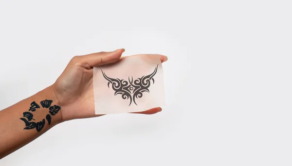 Hand holding Temporary Tattoo paper isolated on soft white background. copy space image