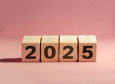 2025, ahşap harf bloklarında gösteriliyor. Pastel pembe arka planda izole edilmiş..