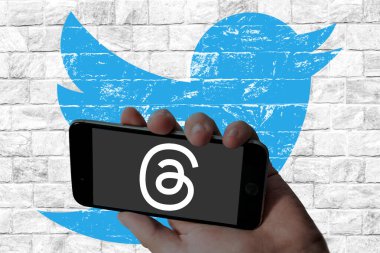  Threads Instagram app logo in holding mobile screen and twitter logo in wall texture background.