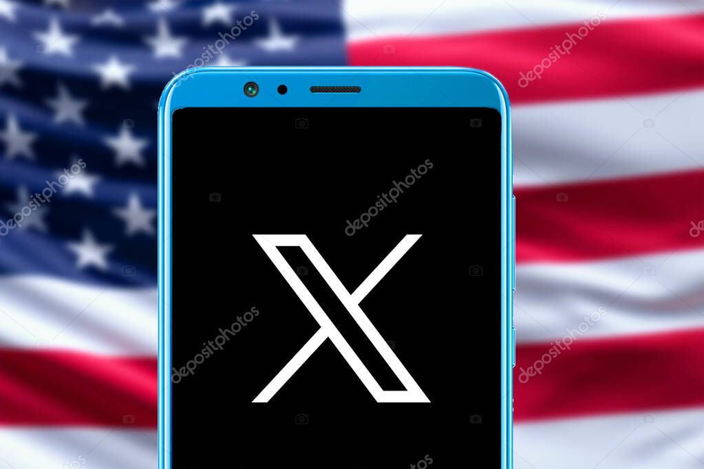 Twitter X logo in mobile screen and USA flag blurred picture in background.