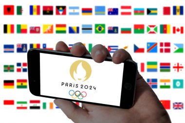 MADURAI, INDIA, 10 HAZİRAN 2024: Cep telefonlarında 2024 Paris Olimpiyatları logosu ve katılımcı ülkelerin bayrak arkaplan fotoğrafları bulanık.