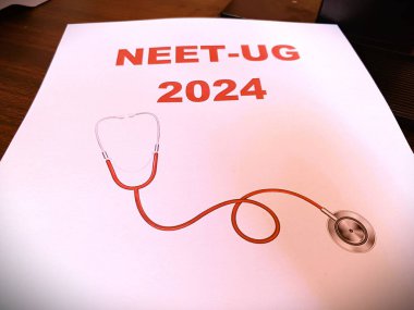NEET UG 2024 'ü steteskopla gösteren basılı bir kağıt. Masada izole edilmiş. gerçek resim. 