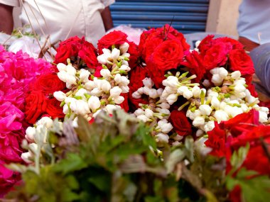 Taze çiçeklerin rengarenk bir çeşidi, ağırlıklı olarak kırmızı güller ve beyaz yasemin, bir pazarda sergileniyor..