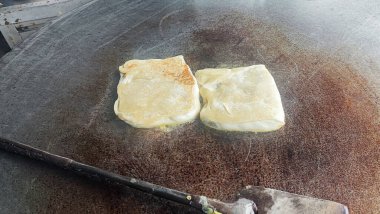 Martabak Durian 'ın, Martabak' ın Endonezya 'daki Geudong pazarında kızgın tavada kızardığını görüyoruz.