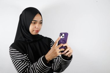 Genç Asyalı Müslüman kadın akıllı telefon kullanıyor.