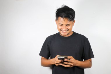 Beyaz arka planda elinde akıllı telefon olan Asyalı genç bir adam.