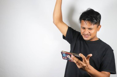 Asyalı genç adam akıllı telefon kullanıyor ve beyaz arkaplanda kopyalama alanı olan boş ekranını işaret ediyor.