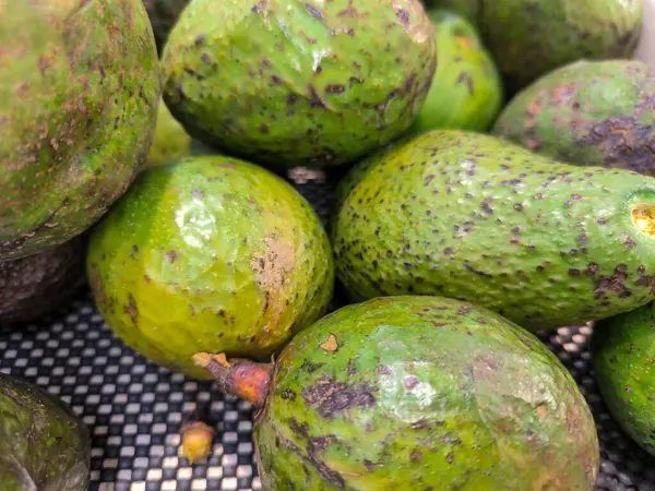 Bir markette sergilenen yeşil ve sarı avokadolar