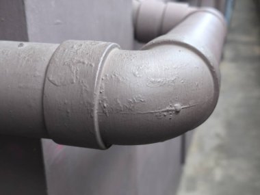 Yakın çekimde, bir dirsek eklemi ve desenli açık kahverengi yüzey içeren bir endüstriyel boru bağlantısı vurgulandı.