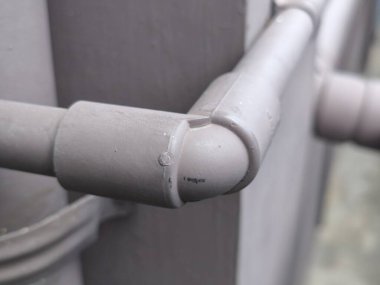 Ayrıntılı bir yakın plan, gri plastik bir boru ve dirsek eklemini gösteriyor, drenaj sisteminin dokusunu ve yapısını vurguluyor..