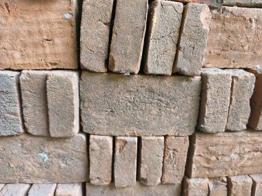 Yapım ve tasarım için ideal olan sert, tanecikli dokularını ve toprak tonlarını ortaya çıkaran, üst üste istiflenmiş kırmızı kil tuğlalarının yakın plan çekimi..