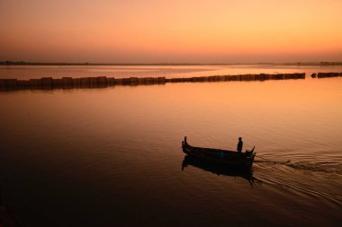 Mandalay 'da, Myanmar' ın en büyük ikinci şehri, gün batımının altında Irrawaddy Nehri boyunca kürek çeken küçük bir tekne vardı..