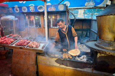 Urumçi, Xinjiang, Çin 'de geleneksel bir pazarda ızgara et ve yerli Uygur yemeği satan satıcılar.