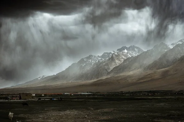 stock image The towering snow-capped mountains next to the Alar Wetland are about to be covered by storm