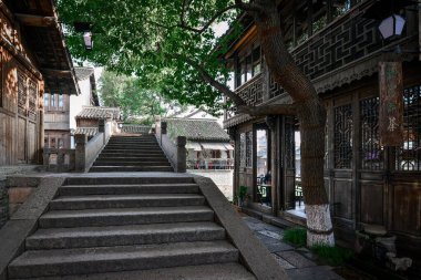 Küçük nehir, ahşap kayıklar, taş köprüler ve güney Çin 'deki küçük bir su kasabasında taş tuğlalarla döşenmiş eski sokak ahşap dükkanları.