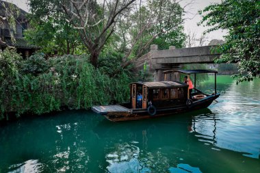 Küçük nehir, ahşap kayıklar, taş köprüler ve güney Çin 'deki küçük bir su kasabasında taş tuğlalarla döşenmiş eski sokak ahşap dükkanları.
