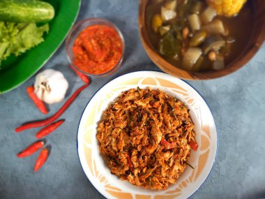 Kırmızı biber dilimleri ve kırmızı biberli fesleğen yapraklı baharatlı kızarmış uskumru ton balığı ve arka planda taze sebze çorbası.