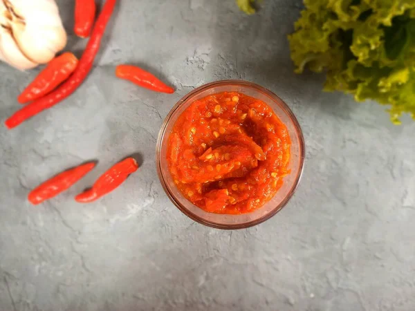 Kırmızı biberli, sarımsaklı ve taze sebzeli cam bir kasede domates sosu (sambal).