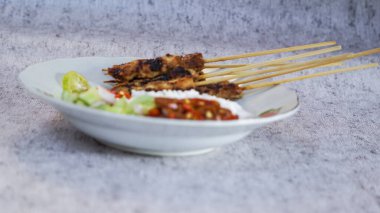 Pilav, turşu, biber sosu ve limonla servis edilen tavuk satay evde yemeye hazır. Renk ve lezzetlerin canlı karışımı duyuları cezbeder. yakın plan