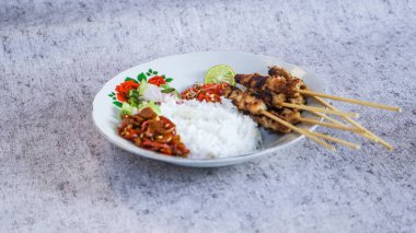 Pilav, turşu, biber sosu ve limonla servis edilen tavuk satay evde yemeye hazır. Renk ve lezzetlerin canlı karışımı duyuları cezbeder. yakın plan