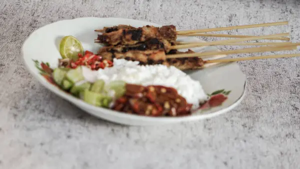 Pilav, turşu, biber sosu ve limonla servis edilen tavuk satay evde yemeye hazır. Renk ve lezzetlerin canlı karışımı duyuları cezbeder. yakın plan