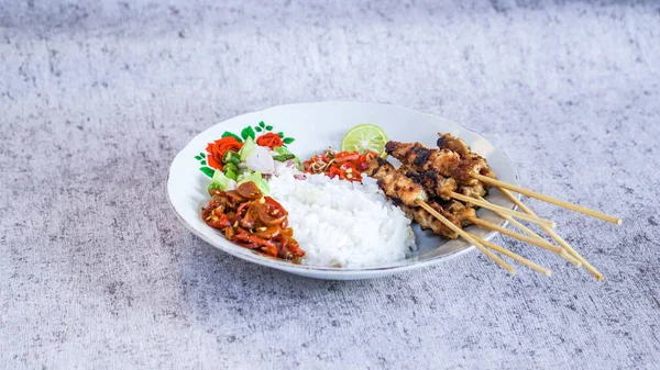 Pilav, turşu, biber sosu ve limonla servis edilen tavuk satay evde yemeye hazır. Renk ve lezzetlerin canlı karışımı duyuları cezbeder. yakın plan
