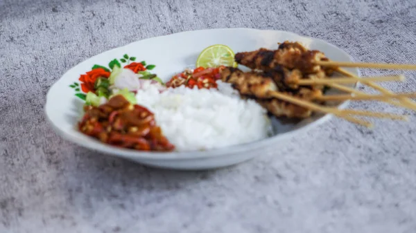 Pilav, turşu, biber sosu ve limonla servis edilen tavuk satay evde yemeye hazır. Renk ve lezzetlerin canlı karışımı duyuları cezbeder. yakın plan