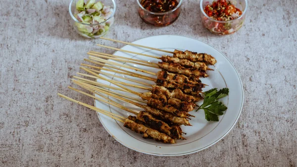 Odada turşu, soya sosu ve sambal matah ile servis edilen bir tabak taze satay, canlı renkleri ve aromaları nefis cazibesine ekleniyor. en üstteki görünüm