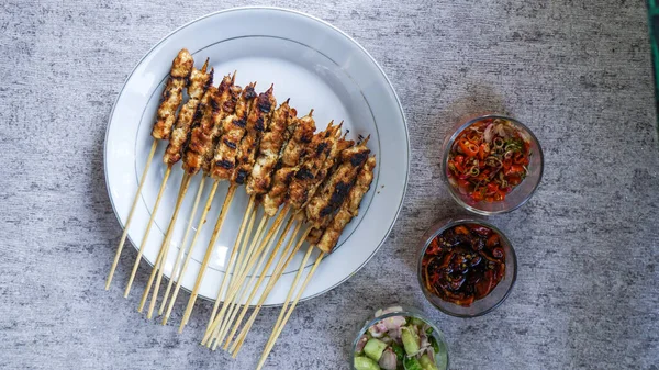 Odada turşu, soya sosu ve sambal matah ile servis edilen bir tabak taze satay, canlı renkleri ve aromaları nefis cazibesine ekleniyor. en üstteki görünüm