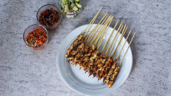 Odada turşu, soya sosu ve sambal matah ile servis edilen bir tabak taze satay, canlı renkleri ve aromaları nefis cazibesine ekleniyor. en üstteki görünüm