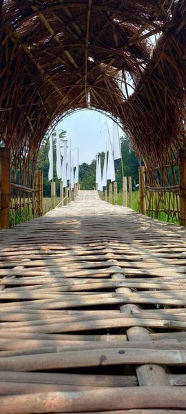 Pirinç tarlalarının kenarındaki Angkringan restoranı Setu Bekasi: Asılı bir bambu köprüsü sazdan çatılı pirinç tarlalarını geçiyor