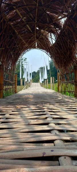 Pirinç tarlalarının kenarındaki Angkringan restoranı Setu Bekasi: Asılı bir bambu köprüsü sazdan çatılı pirinç tarlalarını geçiyor