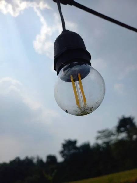 Mavi gökyüzüne asılmış güzel sarı dekoratif ampuller. Edison retro lambasını gökyüzü arka planına ayarla. Kavram fikri.