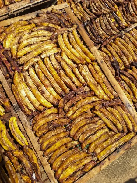 Güneşin altındaki bambu tepsilerde sıralanmış kurumuş muz dilimleri. Yerel lezzet