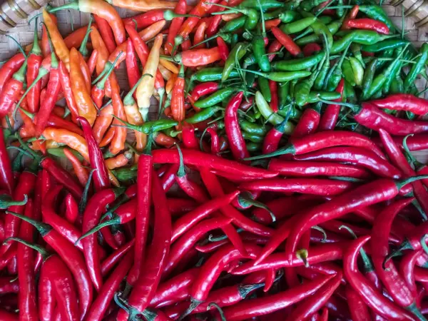Kırsal bambu sepetinde düzenlenmiş kırmızı, yeşil ve turuncu kırmızı biber karışımı.