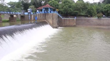Eski bir taş barajı ve taşan şelalesi olan sakin kırsal su deposu geleneksel bir çardağın yanında ve sakin suların üzerinde bir yaya köprüsü.