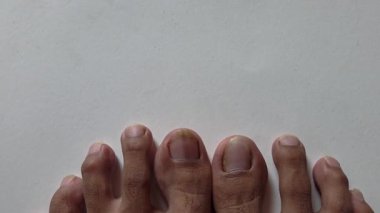 İki insan ayağı, doğal uzun tırnaklar ve beyaz kağıt dokusunda izole edilmiş kaba deri.