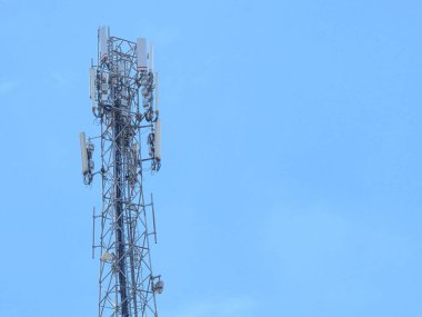 Hücresel ve radyo sinyali iletimi için açık mavi gökyüzüne karşı duran uzun telekomünikasyon kulesi