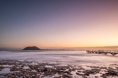 Kumsalda güzel bir sabah. Denizde uzun süre kalmışlar. Sis ve sisin içinde sütlü gün doğumu. Corralejo, Kanarya Adaları, İspanya