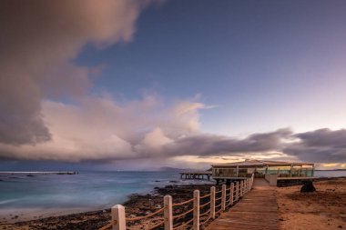 Kumsalda güzel bir sabah. Denizde uzun süre kalmışlar. Sis ve sisin içinde sütlü gün doğumu. Corralejo, Kanarya Adaları, İspanya
