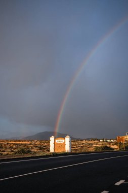 Kum tepelerinin üzerinde gökkuşağı ve bir kum tepesi yolu. Corralejo Ulusal Parkı, Las Palmas Eyaleti, Fuerteventura, Kanarya Adaları, İspanya