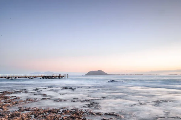 stock image Long exposure over a lava beach. Stony sandy beach in the morning. bay, coast at Corralejo, Las Palmas Province, Spain