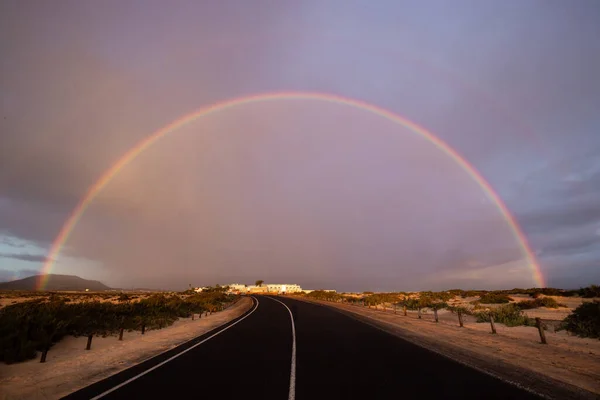 Kum tepelerinin üzerinde gökkuşağı ve bir kum tepesi yolu. Corralejo Ulusal Parkı, Las Palmas Eyaleti, Fuerteventura, Kanarya Adaları, İspanya