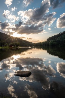 Hayatımda gördüğüm en güzel günbatımlarından biri, bir vadide sakin bir su deposu, yeşil ve bölgede bir orman. Güneş gölde güzel bir şekilde batıyor ve her şey suya yansıyor.